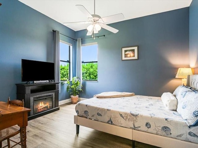 312 148th Ct NE, Bradenton, FL 34212 - bedroom with wood finished floors, a glass covered fireplace, baseboards, and a ceiling fan