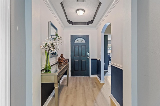 5618 Sheer Bliss Loop, Land O Lakes, FL 34639 - foyer entrance with arched walkways, light wood-style flooring, a tray ceiling, a textured ceiling, and ornamental molding