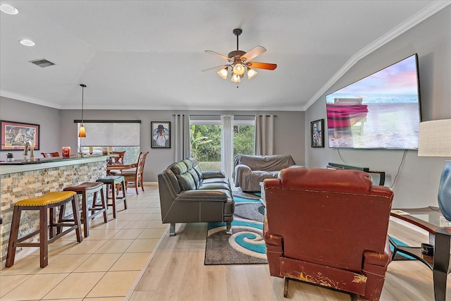 5618 Sheer Bliss Loop, Land O Lakes, FL 34639 - living area with light wood-style flooring, ceiling fan, vaulted ceiling, ornamental molding, and bar area