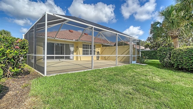 5566 Avellino Pl, Sarasota, FL 34238 - rear view of house featuring glass enclosure, a tile roof, a patio area, a yard, and stucco siding