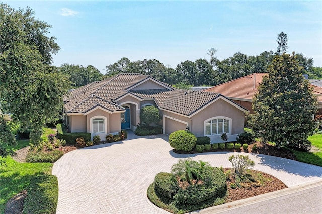 5205 88th St E, Bradenton, FL 34211 - mediterranean / spanish home featuring curved driveway, a garage, a tile roof, and stucco siding