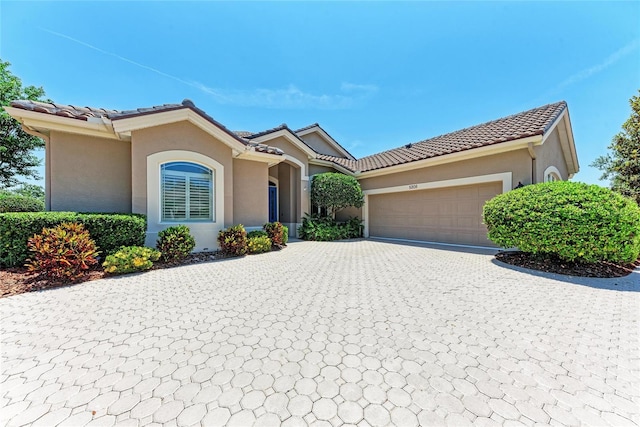 5205 88th St E, Bradenton, FL 34211 - mediterranean / spanish-style house featuring a tiled roof, decorative driveway, a garage, and stucco siding