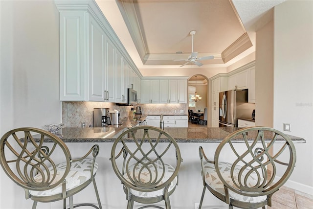 5205 88th St E, Bradenton, FL 34211 - kitchen with a raised ceiling, appliances with stainless steel finishes, a peninsula, ornamental molding, and decorative backsplash