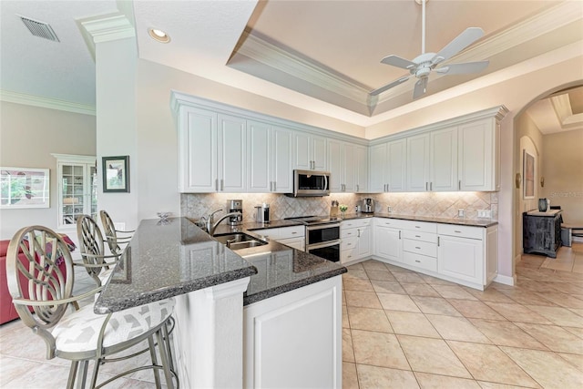 5205 88th St E, Bradenton, FL 34211 - kitchen with a sink, appliances with stainless steel finishes, arched walkways, a peninsula, and decorative backsplash