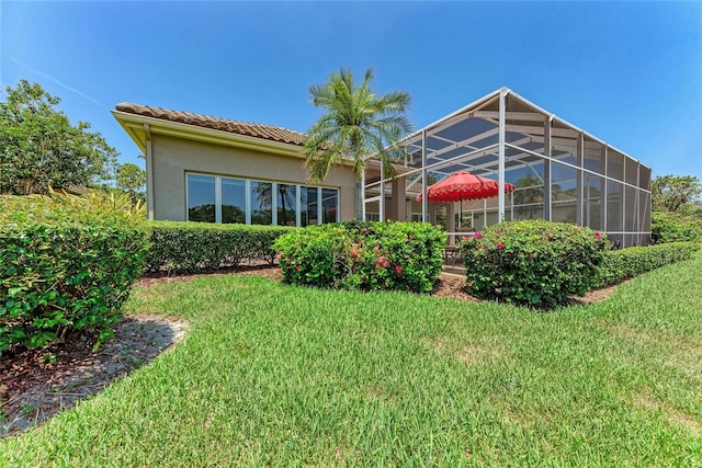 5205 88th St E, Bradenton, FL 34211 - rear view of property with a yard, stucco siding, a tiled roof, and glass enclosure