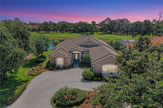 5205 88th St E, Bradenton, FL 34211 - mediterranean / spanish-style home featuring a tiled roof, curved driveway, stucco siding, a water view, and view of wooded area