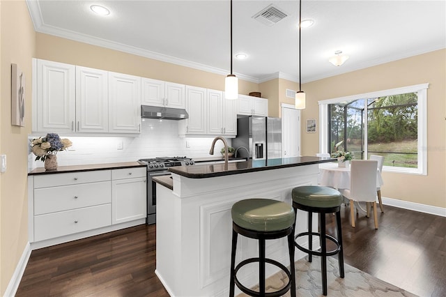 11794 Forest Park Cir, Bradenton, FL 34211 - kitchen featuring appliances with stainless steel finishes, under cabinet range hood, dark countertops, dark wood-style flooring, and ornamental molding