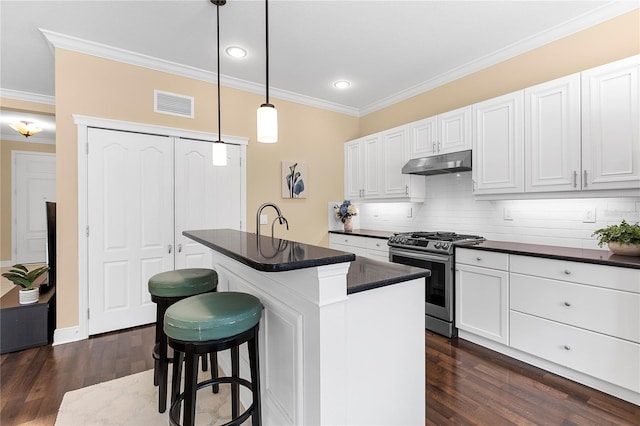 11794 Forest Park Cir, Bradenton, FL 34211 - kitchen with stainless steel gas stove, dark countertops, under cabinet range hood, ornamental molding, and dark wood finished floors