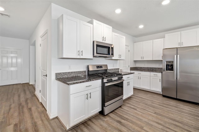 8656 40th Cir E, Palmetto, FL 34221 - kitchen featuring appliances with stainless steel finishes, light wood finished floors, white cabinets, dark stone counters, and recessed lighting