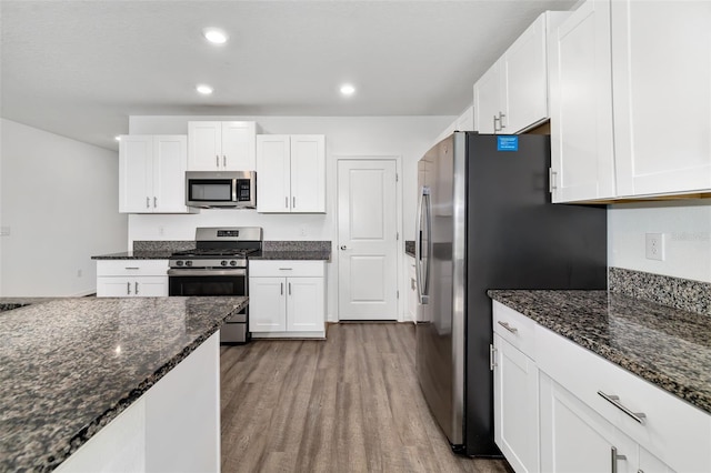 8656 40th Cir E, Palmetto, FL 34221 - kitchen featuring appliances with stainless steel finishes, wood finished floors, white cabinetry, dark stone countertops, and recessed lighting