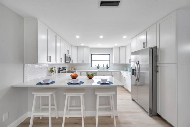5125 Palm Aire Dr, Sarasota, FL 34243 - kitchen featuring appliances with stainless steel finishes, a peninsula, light countertops, backsplash, and recessed lighting