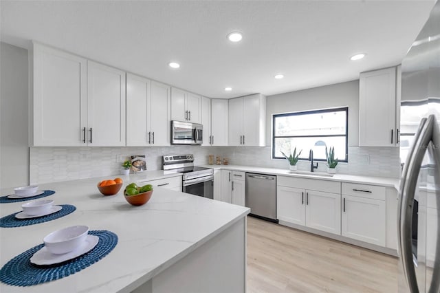 5125 Palm Aire Dr, Sarasota, FL 34243 - kitchen featuring appliances with stainless steel finishes, a sink, light stone countertops, backsplash, and recessed lighting