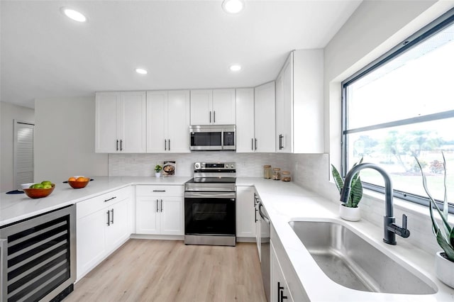 5125 Palm Aire Dr, Sarasota, FL 34243 - kitchen with stainless steel appliances, beverage cooler, a sink, tasteful backsplash, and white cabinetry