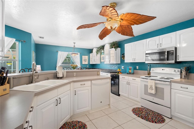 4222 Lanai Dr, Sarasota, FL 34241 - kitchen featuring white appliances, a sink, light tile patterned floors, white cabinets, and a textured ceiling