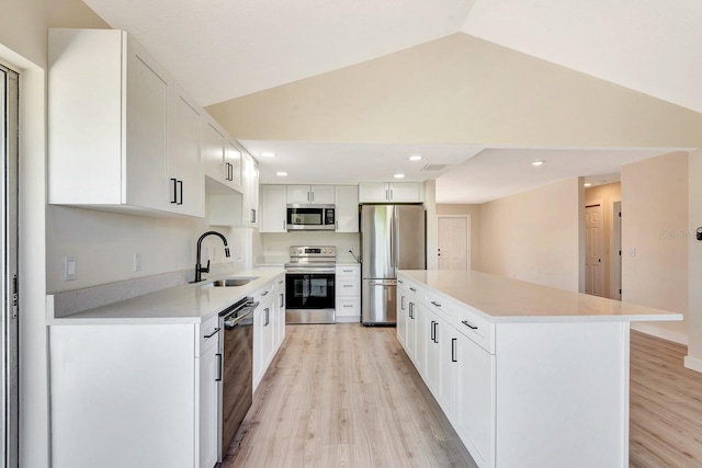 2420 16th St W, Palmetto, FL 34221 - kitchen with appliances with stainless steel finishes, a sink, light wood-style flooring, vaulted ceiling, and a kitchen island