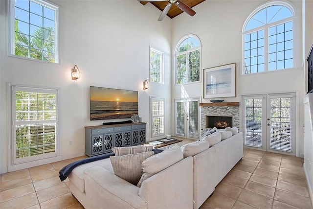 4108 Roberts Point Rd, Sarasota, FL 34242 - tiled living room featuring high vaulted ceiling, a ceiling fan, healthy amount of natural light, wood ceiling with exposed beams, and a stone fireplace