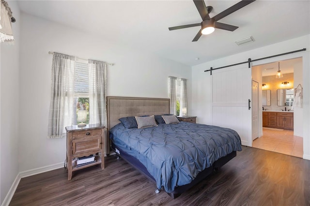 5020 Torrey Pines Run, Bradenton, FL 34211 - bedroom with wood finished floors, a barn door, baseboards, connected bathroom, and ceiling fan