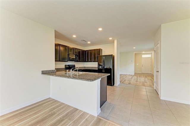 4206 Park Willow Ave, Palmetto, FL 34221 - kitchen with black appliances, dark brown cabinetry, dark stone countertops, recessed lighting, and a peninsula