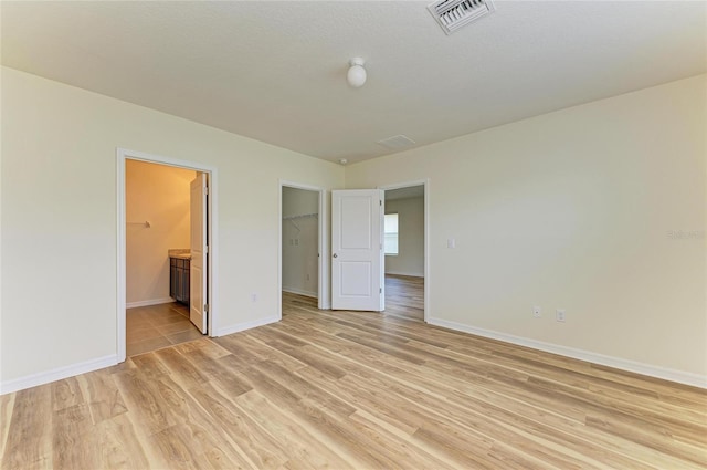 4206 Park Willow Ave, Palmetto, FL 34221 - unfurnished bedroom featuring light wood-style floors, baseboards, a walk in closet, ensuite bath, and a closet