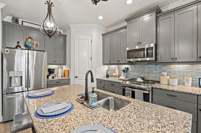 13849 Old Creek Ct, Parrish, FL 34219 - kitchen with appliances with stainless steel finishes, gray cabinetry, a sink, ornamental molding, and light stone countertops