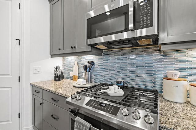 13849 Old Creek Ct, Parrish, FL 34219 - kitchen featuring appliances with stainless steel finishes, gray cabinets, backsplash, and light stone counters