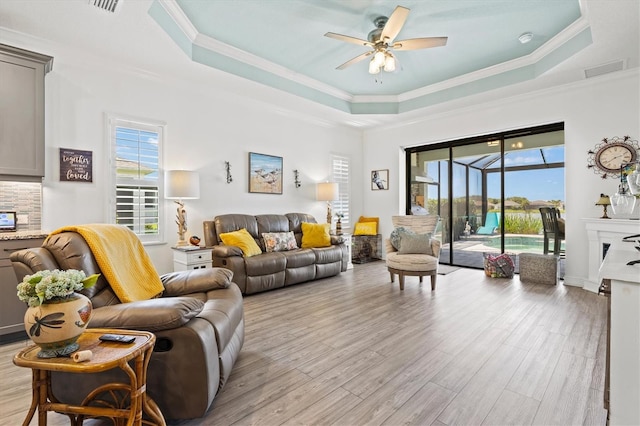 13849 Old Creek Ct, Parrish, FL 34219 - living room featuring a tray ceiling, ceiling fan, healthy amount of natural light, light wood-style floors, and ornamental molding