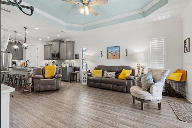 13849 Old Creek Ct, Parrish, FL 34219 - living room featuring crown molding, ceiling fan, light wood-style flooring, recessed lighting, and a tray ceiling