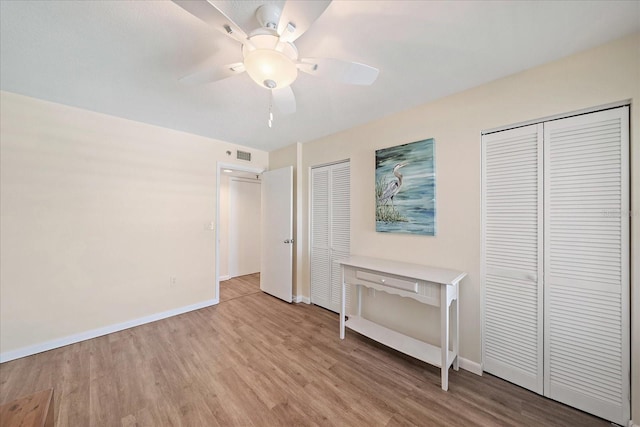 4570 Pinebrook Cir Unit 508, Bradenton, FL 34209 - unfurnished bedroom with multiple closets, wood finished floors, baseboards, and ceiling fan