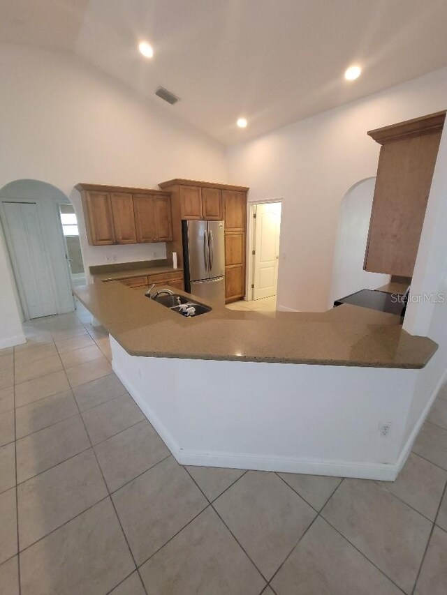 1422 Jakway Rd, North Port, FL 34288 - kitchen with freestanding refrigerator, arched walkways, a sink, brown cabinetry, and high vaulted ceiling
