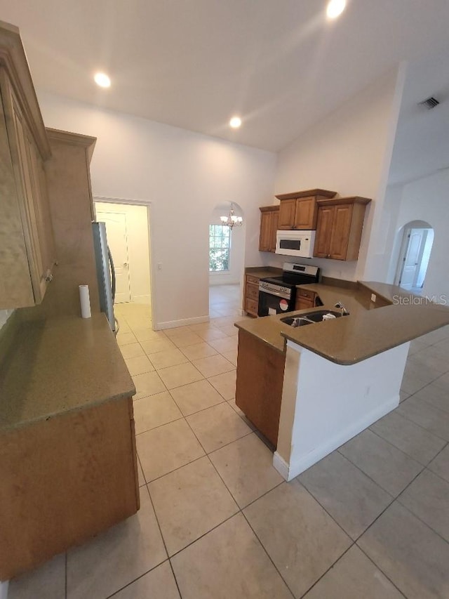 1422 Jakway Rd, North Port, FL 34288 - kitchen featuring appliances with stainless steel finishes, arched walkways, brown cabinets, light tile patterned floors, and recessed lighting