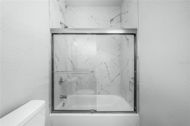 703 Salamanca Ct, Sebring, FL 33870 - bathroom featuring combined bath / shower with glass door, toilet, and a textured wall