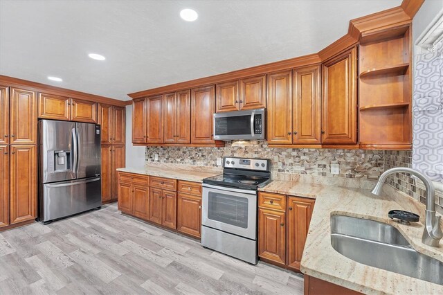 513 25th Ave W, Bradenton, FL 34205 - kitchen featuring stainless steel appliances, a sink, brown cabinetry, light wood-style floors, and open shelves