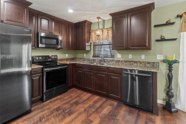 4758 Breezy Pines Blvd, Sarasota, FL 34232 - kitchen with stainless steel appliances, a sink, stone countertops, dark wood-type flooring, and dark brown cabinetry