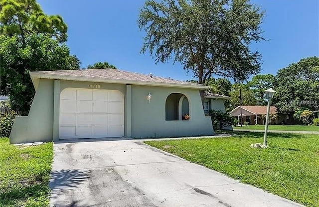 8730 Filson Pl, Sarasota, FL 34231 - view of front of home featuring stucco siding, a front lawn, driveway, and an attached garage