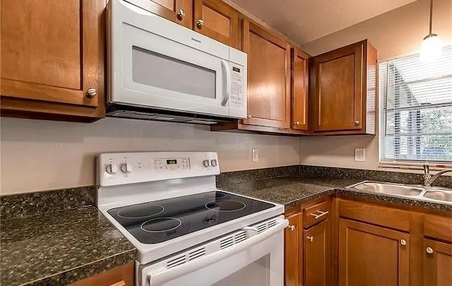 8730 Filson Pl, Sarasota, FL 34231 - kitchen featuring white appliances, brown cabinetry, a sink, and dark countertops