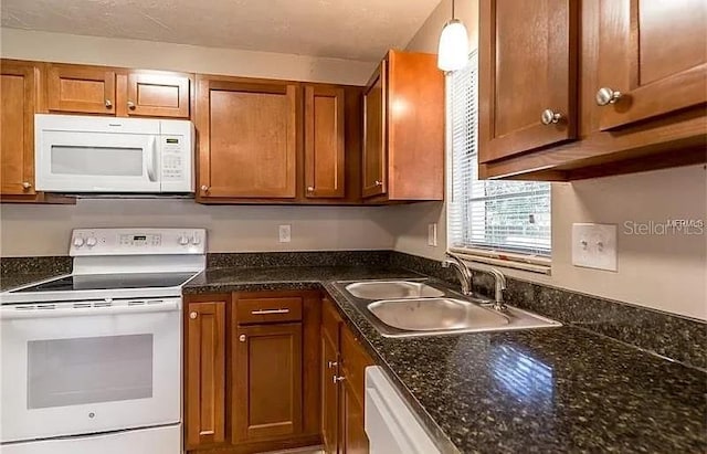8730 Filson Pl, Sarasota, FL 34231 - kitchen with white appliances, brown cabinetry, a sink, and dark stone countertops