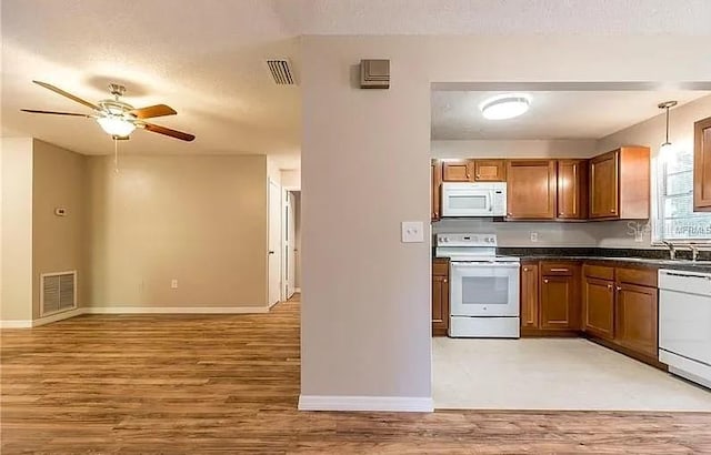 8730 Filson Pl, Sarasota, FL 34231 - kitchen with white appliances, dark countertops, a ceiling fan, light wood-type flooring, and baseboards