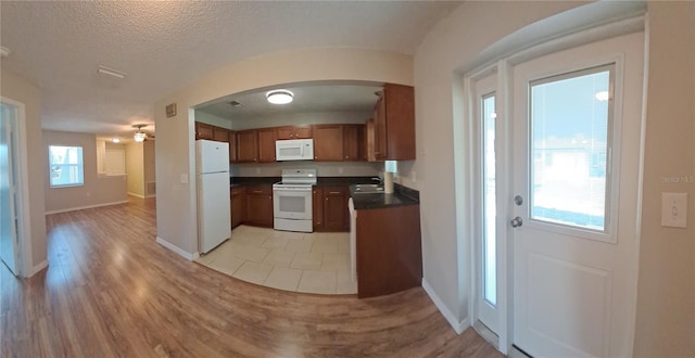 8730 Filson Pl, Sarasota, FL 34231 - kitchen with white appliances, a sink, dark countertops, brown cabinetry, and ceiling fan