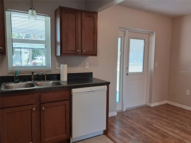 8730 Filson Pl, Sarasota, FL 34231 - kitchen featuring dishwasher, a sink, dark countertops, light wood-style floors, and baseboards