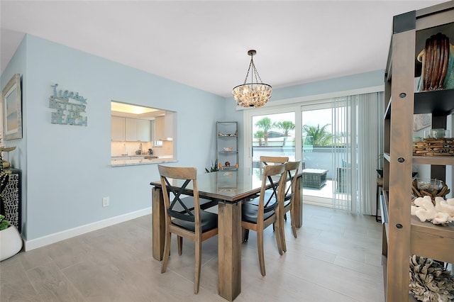 1001 Point Of Rocks Rd Unit 207, Sarasota, FL 34242 - dining space featuring a chandelier, light wood-style floors, and baseboards