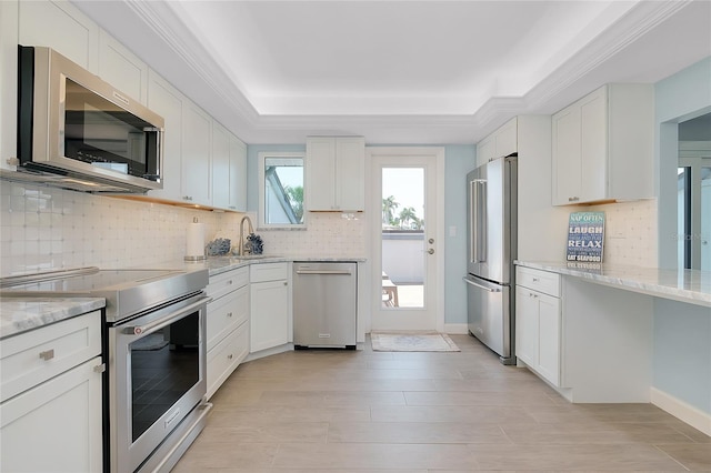 1001 Point Of Rocks Rd Unit 207, Sarasota, FL 34242 - kitchen featuring appliances with stainless steel finishes, decorative backsplash, a tray ceiling, light stone countertops, and white cabinetry