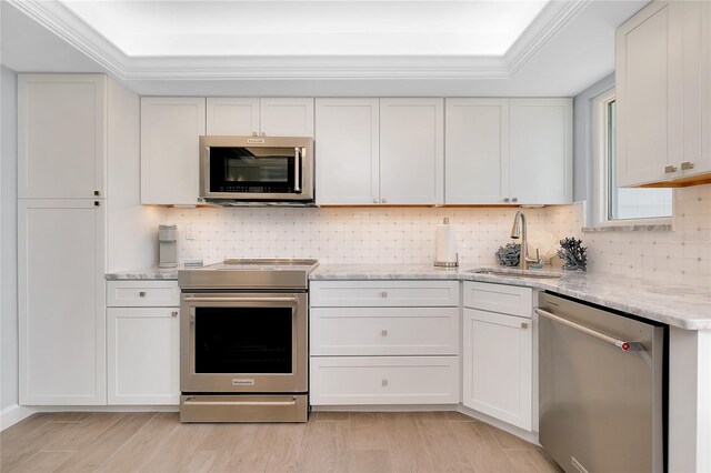 1001 Point Of Rocks Rd Unit 207, Sarasota, FL 34242 - kitchen with appliances with stainless steel finishes, a sink, backsplash, white cabinets, and crown molding