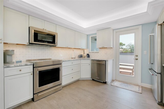 1001 Point Of Rocks Rd Unit 207, Sarasota, FL 34242 - kitchen with stainless steel appliances, tasteful backsplash, light stone countertops, white cabinets, and a raised ceiling
