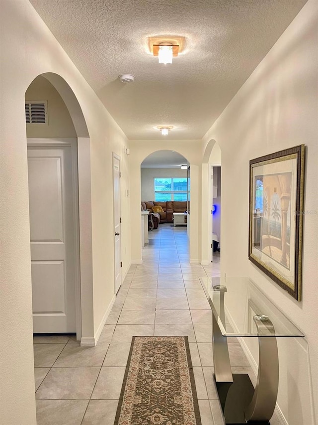 2410 Mizner Bay Ave, Bradenton, FL 34208 - hallway with a textured ceiling, light tile patterned floors, arched walkways, and baseboards