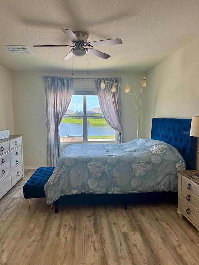2410 Mizner Bay Ave, Bradenton, FL 34208 - bedroom with wood finished floors, a textured ceiling, a water view, and ceiling fan