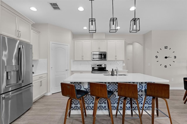 1896 Napoli Dr, Saint Cloud, FL 34771 - kitchen featuring stainless steel appliances, light wood finished floors, arched walkways, recessed lighting, and light countertops