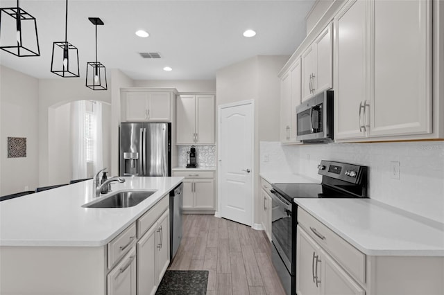 1896 Napoli Dr, Saint Cloud, FL 34771 - kitchen featuring appliances with stainless steel finishes, a sink, arched walkways, decorative light fixtures, and light wood-style flooring