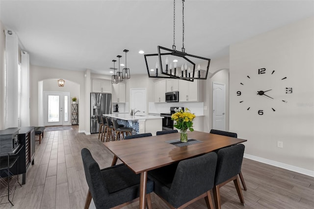 1896 Napoli Dr, Saint Cloud, FL 34771 - dining area with arched walkways, light wood-type flooring, baseboards, recessed lighting, and a chandelier