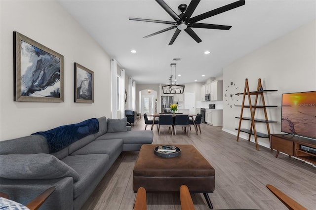 1896 Napoli Dr, Saint Cloud, FL 34771 - living room featuring light wood finished floors, a ceiling fan, recessed lighting, arched walkways, and a chandelier
