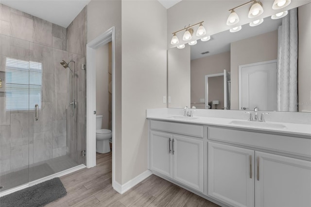 1896 Napoli Dr, Saint Cloud, FL 34771 - bathroom with toilet, double vanity, a shower stall, wood finished floors, and baseboards